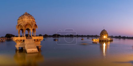 Panoramic view of historic Chhatri, an elevated dome pavilions in Gadisar lake, Rajasthan, India shot during twilight.