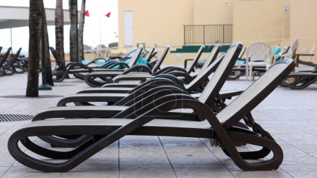Téléchargez les photos : Rangée de chaises longues côté piscine dans une station balnéaire. - en image libre de droit