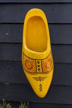 Téléchargez les photos : Yellow large Dutch traditional wooden shoe on the black wall. The Netherlands - en image libre de droit