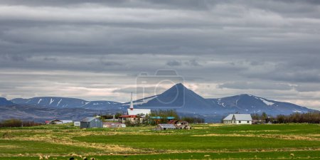 Iglesia en el pequeño pueblo de Brogans, Islandia bajo el cielo nublado.