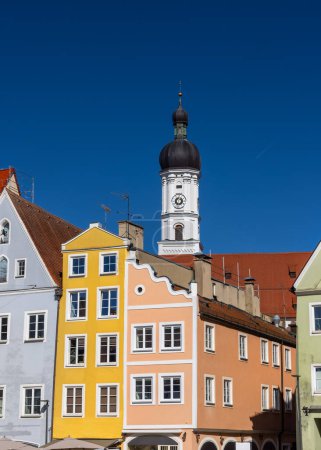 Church of the Assumption of Mary and colorful buildings against blue sky in Landsberg city Germany.