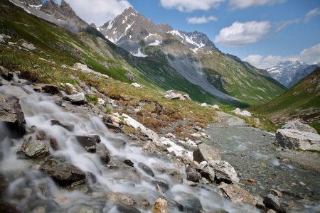 Photo for A mountain stream located along the Chaviere valley, Pralognan la Vanoise,Vanoise National Park, Northern French Alps, Tarentaise, Savoie, France, surrounded by mountains and glaciers - Royalty Free Image