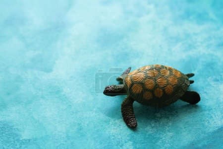 Foto de Tortuga de juguete verde sobre un fondo de acuarela azul brillante - Imagen libre de derechos