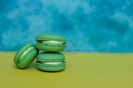 Green macarons on a blue and yellow background with copy space