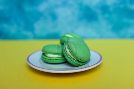 Green macarons on a blue and yellow background with copy space