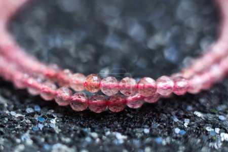 Beautiful pink strawberry quartz beads on a black glitter background close-up macro photo