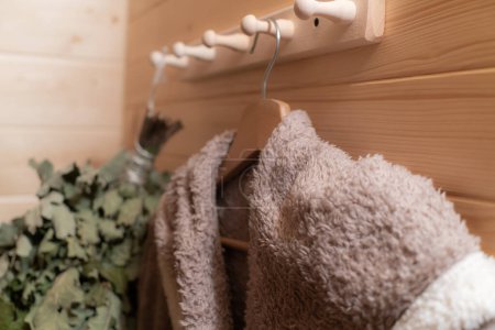 Téléchargez les photos : Accessoires prêts pour le sauna - peignoir, balai et serviette. Concept de bains publics russes. - en image libre de droit