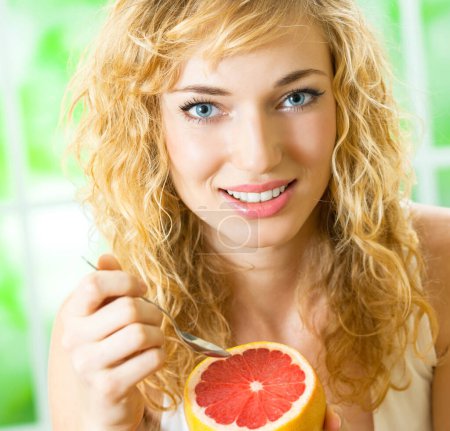 Photo for Cheerful blond woman eating grapefruit - Royalty Free Image