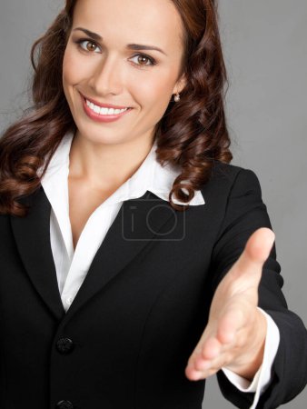 Foto de Retrato de joven alegre hermosa mujer de negocios dando la mano para el apretón de manos, sobre fondo gris - Imagen libre de derechos