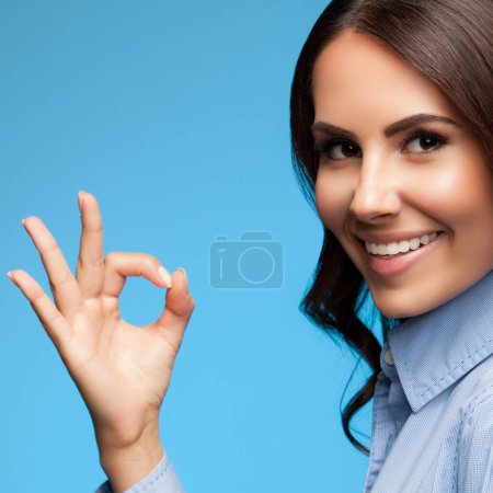 Foto de Retrato de feliz sonrisa mostrando gesto bien mujer de negocios, sobre fondo azul, con copyspace. Concepto publicitario. - Imagen libre de derechos
