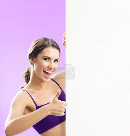 Photo for Cheerful young woman in fitness wear showing blank signboard or copyspace, on rose background - Royalty Free Image