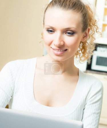 Téléchargez les photos : Joyeux jeune femme travaillant avec un ordinateur portable, à la maison - en image libre de droit