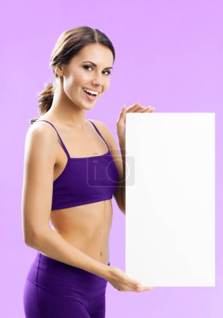 Foto de Joven alegre en ropa de fitness mostrando letrero en blanco o espacio de copia, sobre fondo rosa - Imagen libre de derechos
