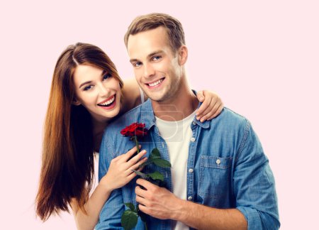 Photo for Portrait of young happy hugging couple with flower, close to each other, with smile. Caucasian models in love, relationship, dating, flirting, lovers, romantic concept. - Royalty Free Image