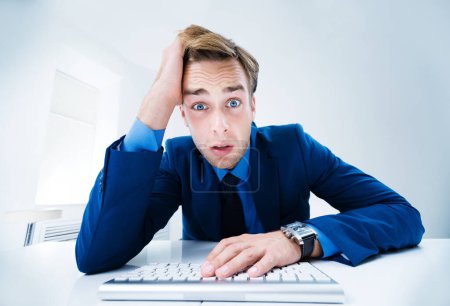 Photo for Tired, surprised or sad businessman in blue suit, working with computer at office. Success in business, job and education concept. - Royalty Free Image