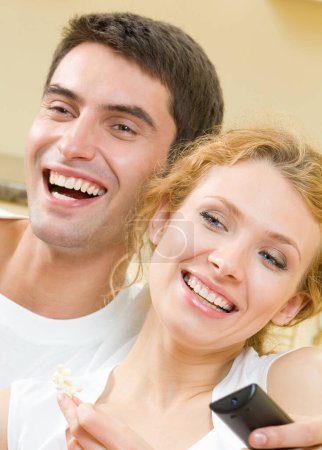 Téléchargez les photos : Joyeux jeune couple regardant la télévision ensemble - en image libre de droit