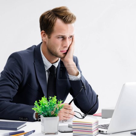 Photo for Stressed, tired businessman or heaving headache, holding his head, in black suit, working with laptop computer at office. Business fall, job and education concept. - Royalty Free Image