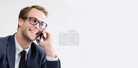 Photo for Young happy smiling businessman in glasses and black suit with cellphone, with copyspace area for slogan or text message. Success in business, job and education concept. - Royalty Free Image