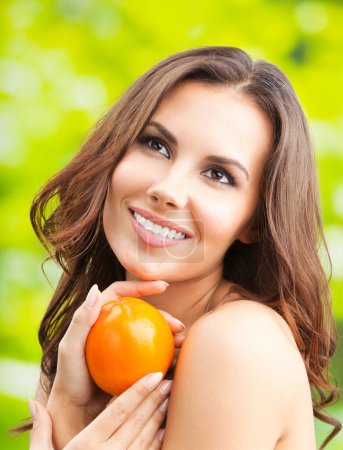 Young woman with persimmon fruit, outdoors