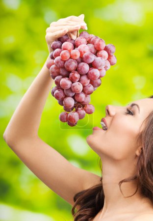 Téléchargez les photos : Jeune femme souriante heureuse avec des raisins, à l'extérieur - en image libre de droit