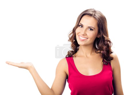 Téléchargez les photos : Joyeux sourire jeune femme en vêtements décontractés rouge intelligent, montrant quelque chose ou copyspace pour le texte ou le slogan, isolé sur fond blanc - en image libre de droit