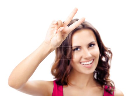 Foto de Feliz joven sonriente vestida de rojo mostrando dos dedos o gesto de victoria, aislada sobre fondo blanco. Enfoque selectivo en la mano. - Imagen libre de derechos
