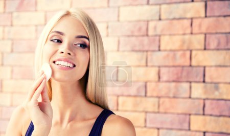 Téléchargez les photos : Joyeux sourire belle femme blonde, nettoyer la peau par coton pad, à la maison, avec zone de copyspace pour slogan ou message texte. Composition horizontale de la bannière. - en image libre de droit