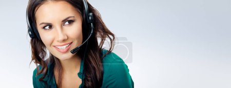 Photo for Portrait of happy smiling cheerful beautiful female phone operator in headset, green confident clothing, empty copyspace area for slogan or advertising text message, over grey background. Call center and customer support service concept. - Royalty Free Image