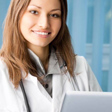 Téléchargez les photos : Portrait de femme médecin joyeux travaillant avec un ordinateur portable au bureau - en image libre de droit