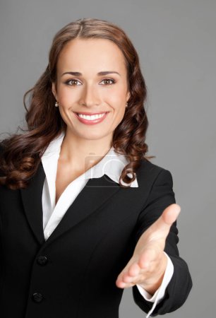 Téléchargez les photos : Portrait de jeune femme d'affaires joyeuse donnant main pour poignée de main, sur fond gris - en image libre de droit