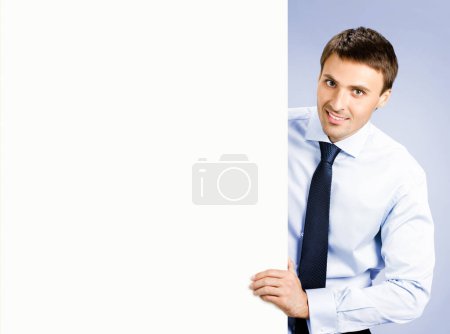 Foto de Retrato de feliz joven hombre de negocios sonriente mostrando letrero en blanco, sobre fondo violeta - Imagen libre de derechos