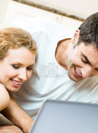 Téléchargez les photos : Couple joyeux travaillant avec un ordinateur portable ensemble, à la maison - en image libre de droit