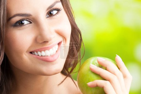 Téléchargez les photos : Jeune femme souriante heureuse avec pomme, à l'extérieur - en image libre de droit