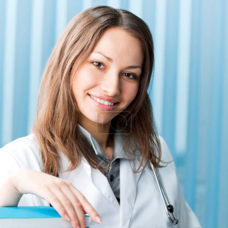 Photo for Portrait of cheerful female doctor with books at office - Royalty Free Image