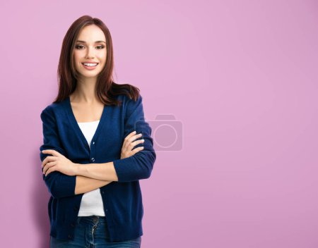 Foto de Retrato de mujer joven sonriente en ropa casual azul inteligente con brazos cruzados, sobre fondo púrpura, con espacio para eslogan, publicidad o mensaje de texto - Imagen libre de derechos