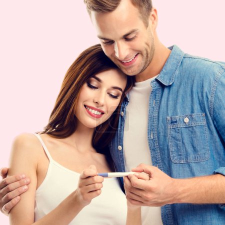 Photo for Young amorous happy couple, finding out results of a pregnancy test, over pink background. Caucasian models - in love, relationship, dating, happy lovers, family concept. - Royalty Free Image