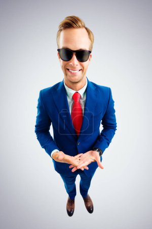 Photo for So what?! Portrait of funny young businessman in sunglasses, blue suit and red tie, top angle view shot, over grey background. Business concept. - Royalty Free Image
