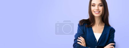 Foto de Retrato de mujer sonriente en ropa casual de color azul inteligente con brazos cruzados, sobre fondo violeta, con copyspace para eslogan, publicidad o mensaje de texto. Composición del estandarte. - Imagen libre de derechos