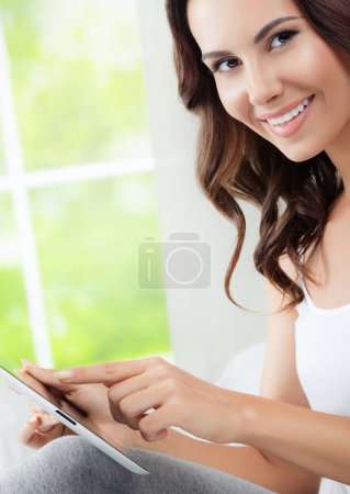 Foto de Mujer joven alegre usando tableta PC, en casa - Imagen libre de derechos