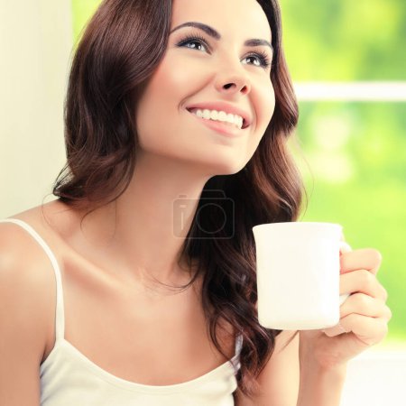 Foto de Retrato de una hermosa joven bebiendo café o té, en casa - Imagen libre de derechos