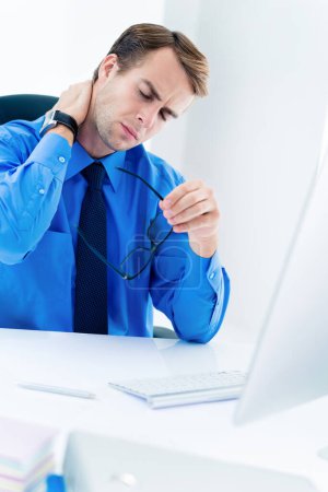 Téléchargez les photos : Homme d'affaires frustré, épuisé ou fatigué en chemise bleue, avec lunettes, col effleurant, avec ordinateur de bureau au bureau. - en image libre de droit