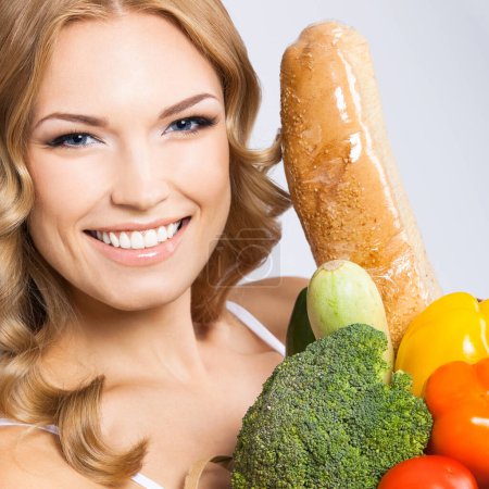 Téléchargez les photos : Souriant jeune belle femme avec de la nourriture crue végétarienne saine, sur fond gris - en image libre de droit