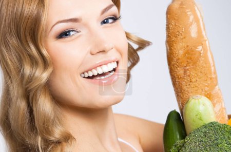Téléchargez les photos : Souriant jeune belle femme avec de la nourriture crue végétarienne saine, sur fond gris - en image libre de droit