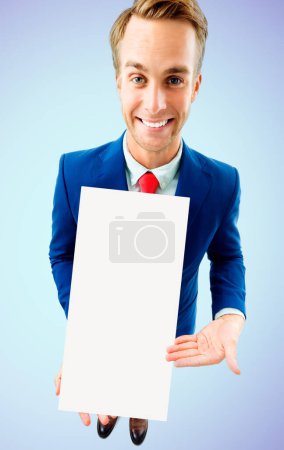 Photo for Businessman in confident suit and red tie, showing blank signboard with copy space area for advertising text or slogan, on blue background. Business concept. - Royalty Free Image