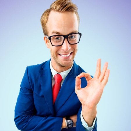 Photo for OK! Funny happy businessman in glasses, confident suit and red tie, showing okay gesture or zero, over blue background. Business concept. - Royalty Free Image