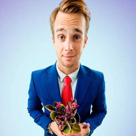 Téléchargez les photos : Homme d'affaires drôle en costume confiant et cravate rouge, tenant pot de fleurs avec des fleurs, sur fond bleu. - en image libre de droit