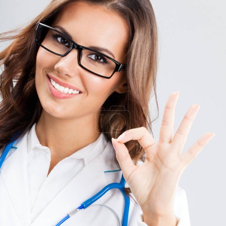 Happy smiling doctor showing okay gesture, over grey background