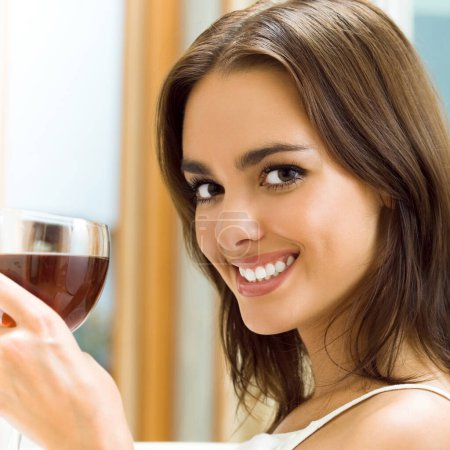 Téléchargez les photos : Portrait de jeune femme souriante heureuse avec un verre de vin rouge - en image libre de droit