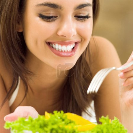 Téléchargez les photos : Joyeux sourire jeune belle femme avec salade de légumes végétariens, à la maison - en image libre de droit
