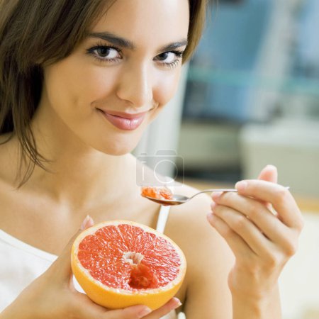 Photo for Young beautiful woman eating grapefruit at home - Royalty Free Image